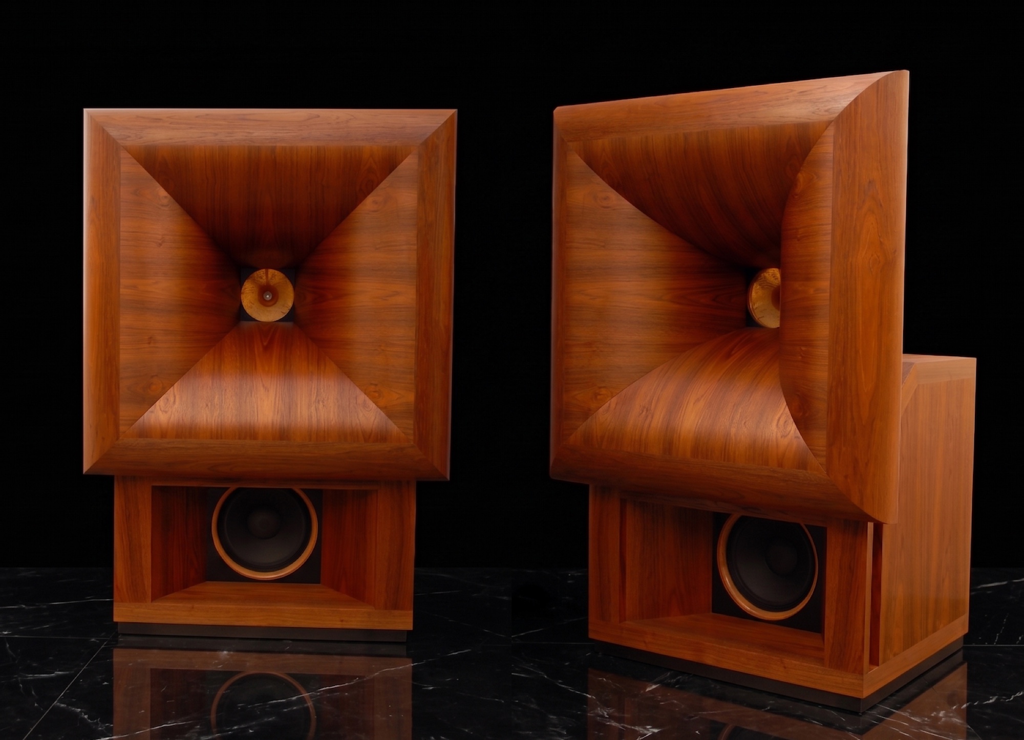 A pair of Semrad Audio walnut horn speakers on a black marble floor, the geometric horn mouths and bass cabinets revealed in even studio light.